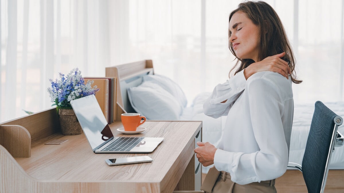 femme souffrant de douleurs au cou assise près de son bureau et travaillant avec son ordinateur