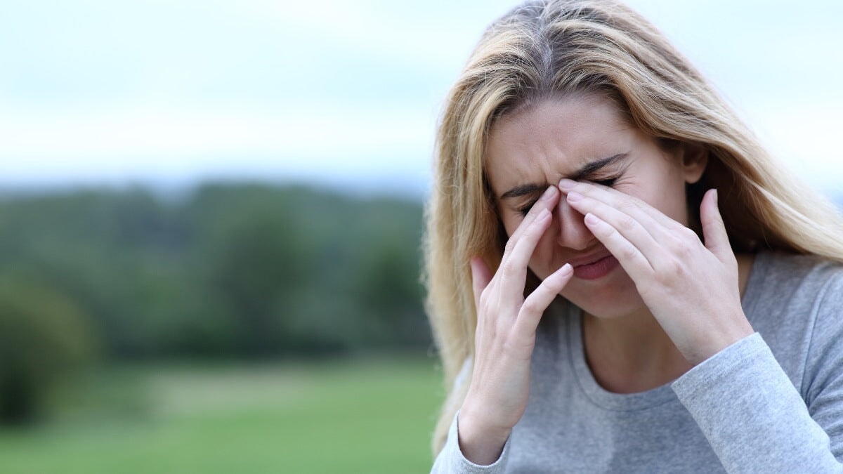 une femme se gratte les yeux qui démangent à l'extérieur