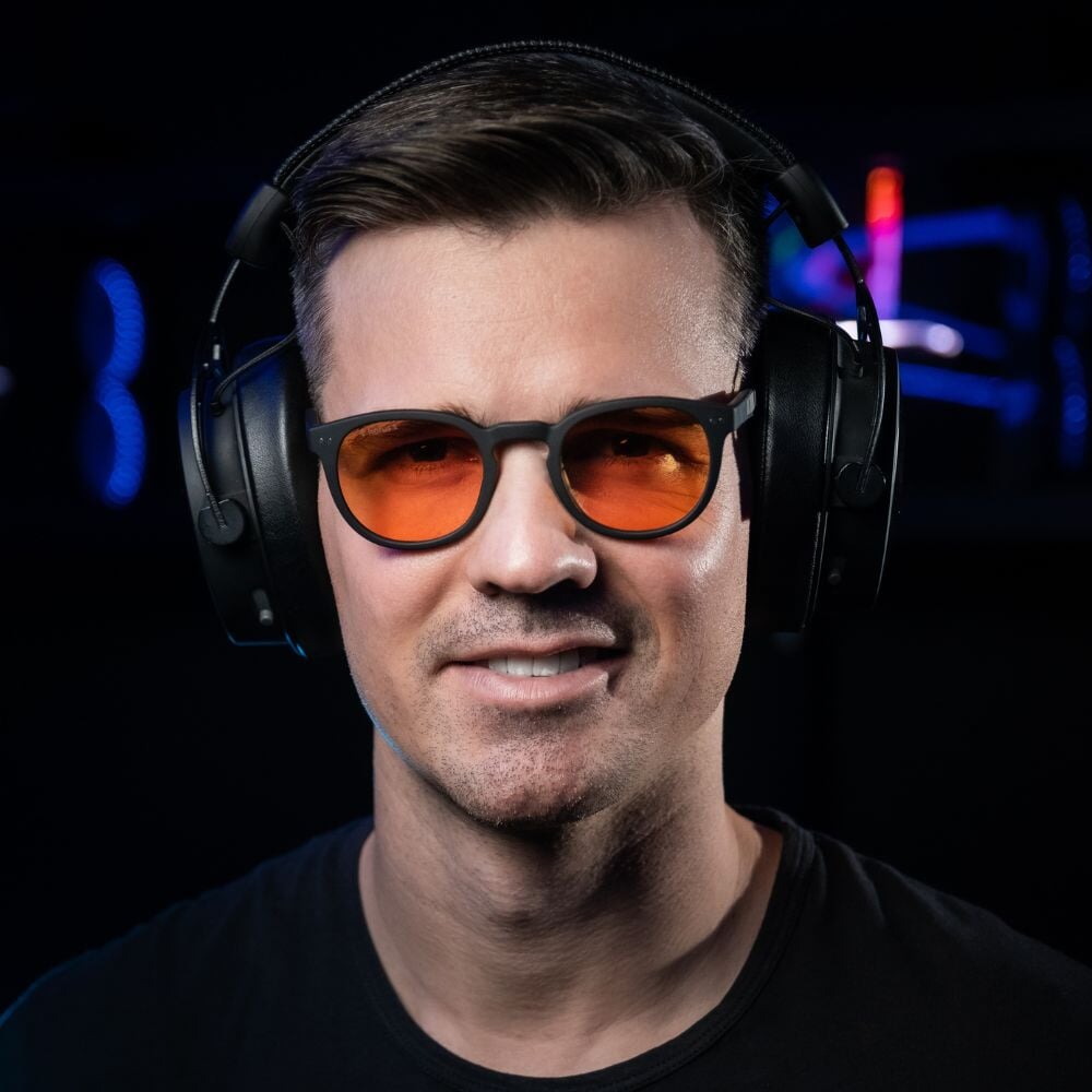 Notre cofondateur Matthieu porte les lunettes gamer urban revolution avec verre ambré et un casque audio sur fond noir de face