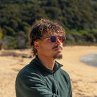 Homme portant les lunettes Ushuaia Sun sur la plage avec beaucoup de végétation en arrière plan