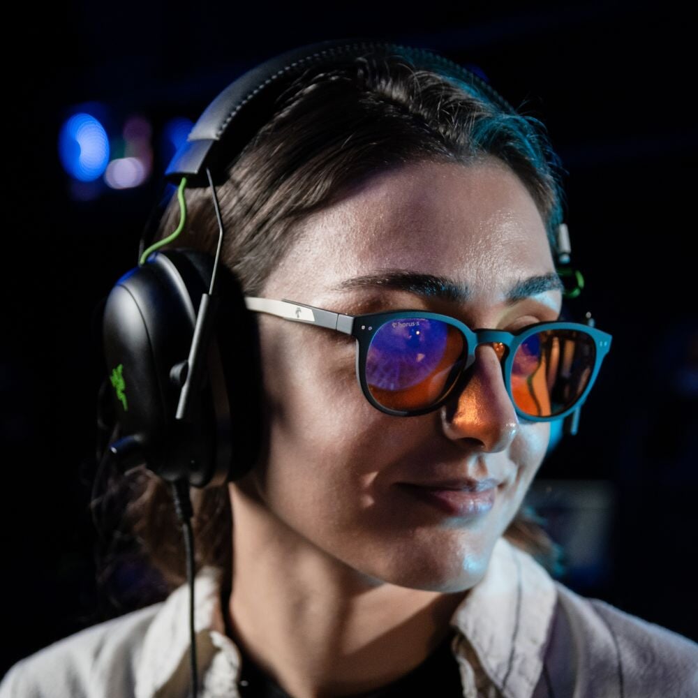 Notre modèle Hélène porte les lunettes gamer urban revolution avec verre ambré et un casque audio sur fond noir de profil